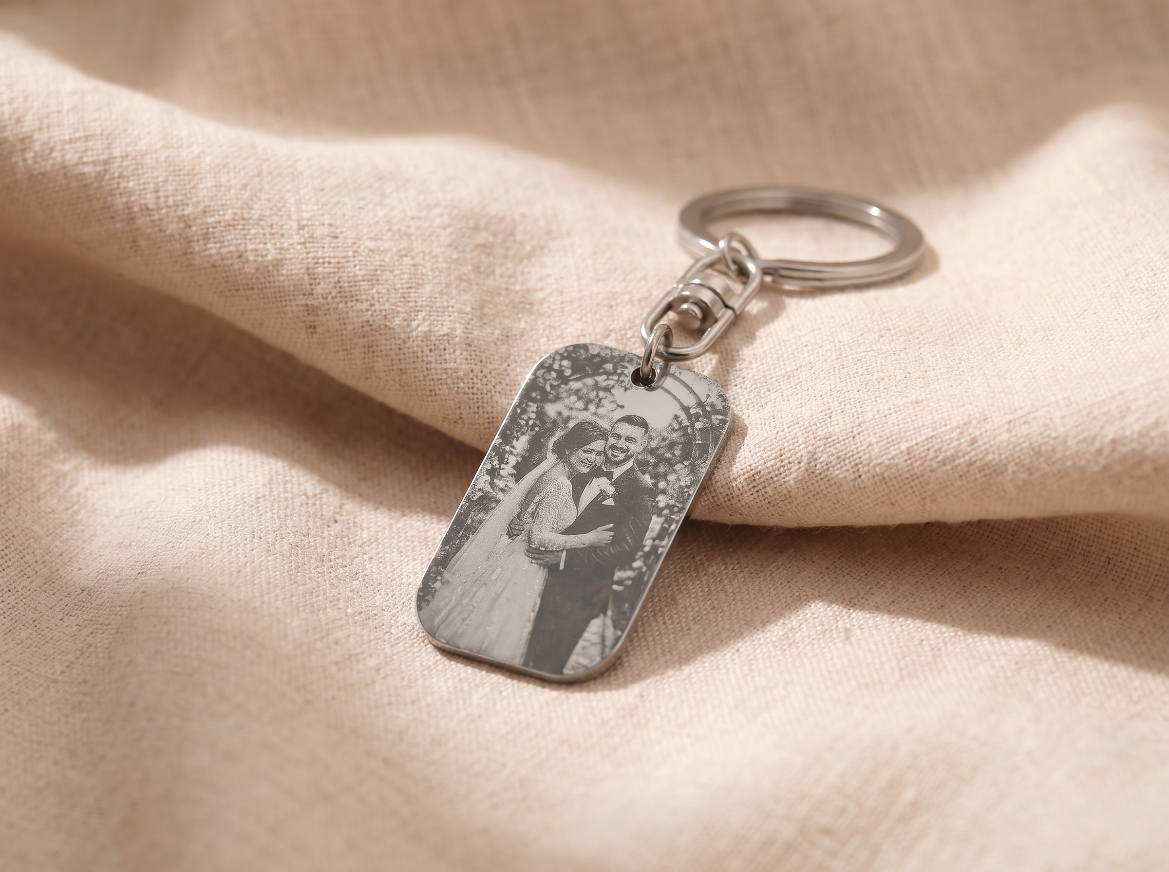 Engraved personalised name tag keyring resting on a kitchen bench beside a set of house keys