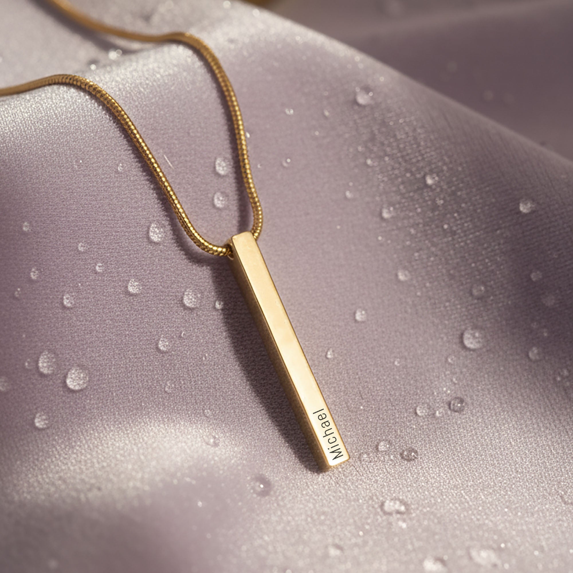 Belle Fever Bar Personalised Necklace — gold vertical bar pendant styled on soft fabric, a refined personalised jewellery piece symbolising simplicity and personal meaning.