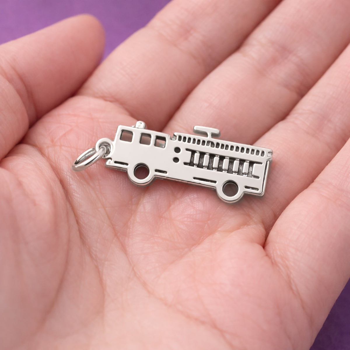 Belle Fever silver fire truck charm close-up in hand, personalised firefighter jewellery charm