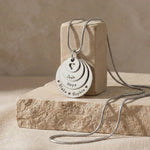 Belle Fever Tower of Love necklace with multiple engraved disc charms, styled on a natural stone surface