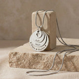 Belle Fever Tower of Love necklace with multiple engraved disc charms, styled on a natural stone surface