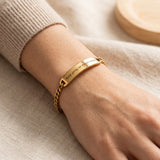 Woman wearing gold bar bracelet with custom engraving on plate design