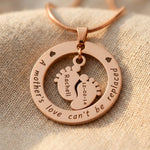 Close up of Can’t Be Replaced Necklace showing engraved message and baby feet charms detail design
