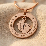 Close up of Can’t Be Replaced Necklace showing engraved message and baby feet charms detail design