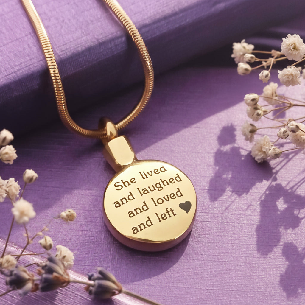 Belle Fever Circle Cremation Necklace in gold, engraved memorial pendant on soft purple background with dried flowers, personalised ashes keepsake jewellery, sympathy gift for loss remembrance.