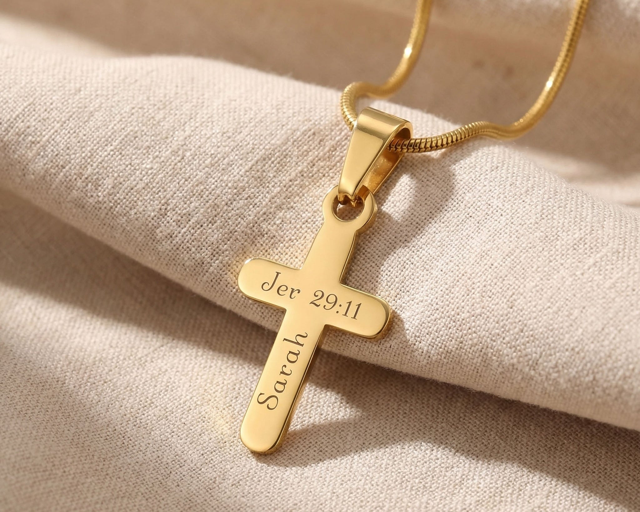 Gold cross name necklace with engraved name on cross pendant displayed on neutral background