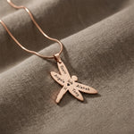 Dragonfly Necklace with Custom Engraved Names by Belle Fever in rose gold on textured taupe fabric, symbolic strength and transformation gift for women.