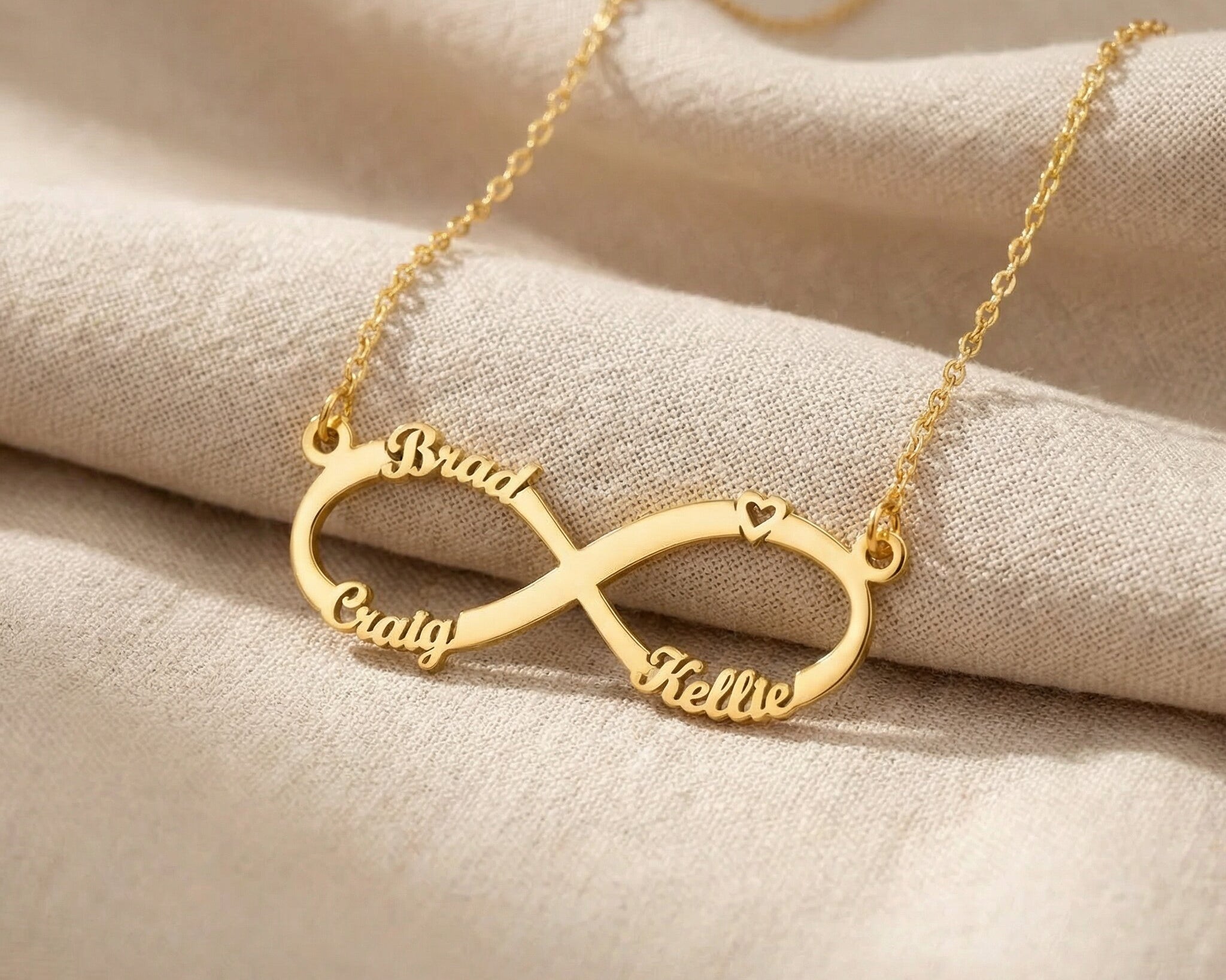 Gold infinity name necklace with custom name on infinity pendant displayed on neutral background