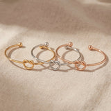 Knot bangle tone comparison showing gold, silver and rose gold symbolic bracelet finishes
