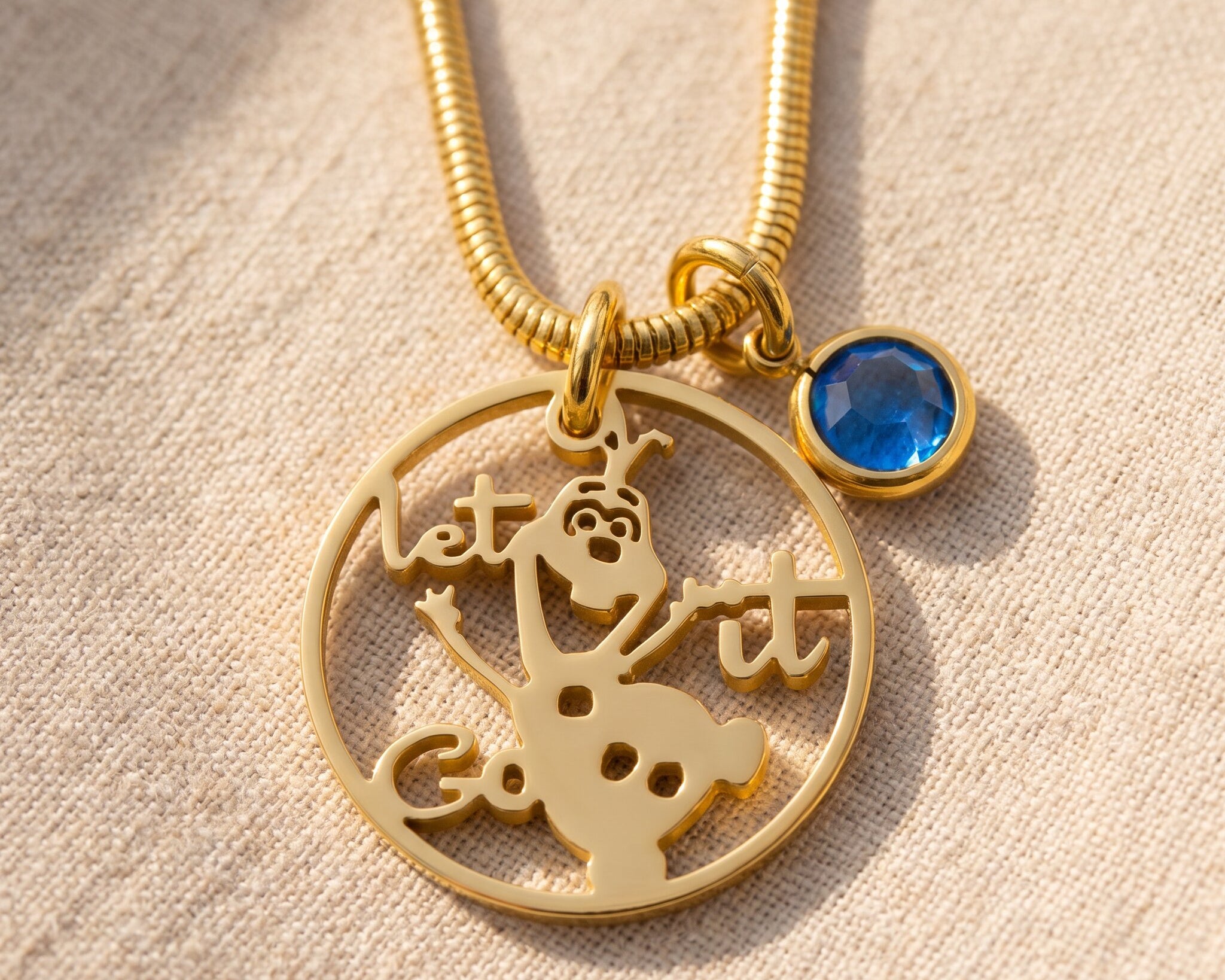 Melting snowman birthstone necklace in gold with unique design and blue birthstone charm
