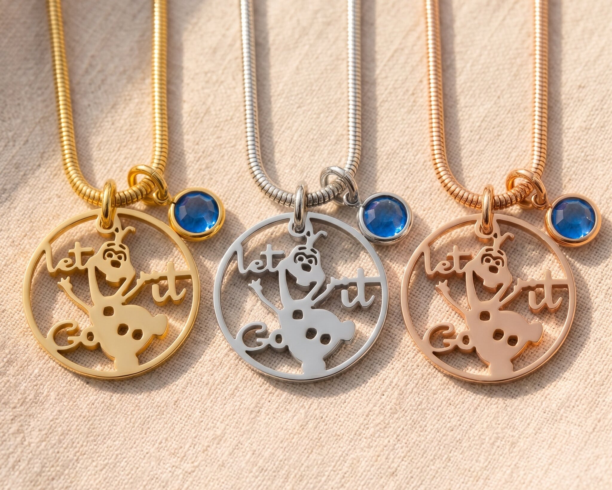 Melting snowman birthstone necklace tone comparison showing gold, silver and rose gold design finishes