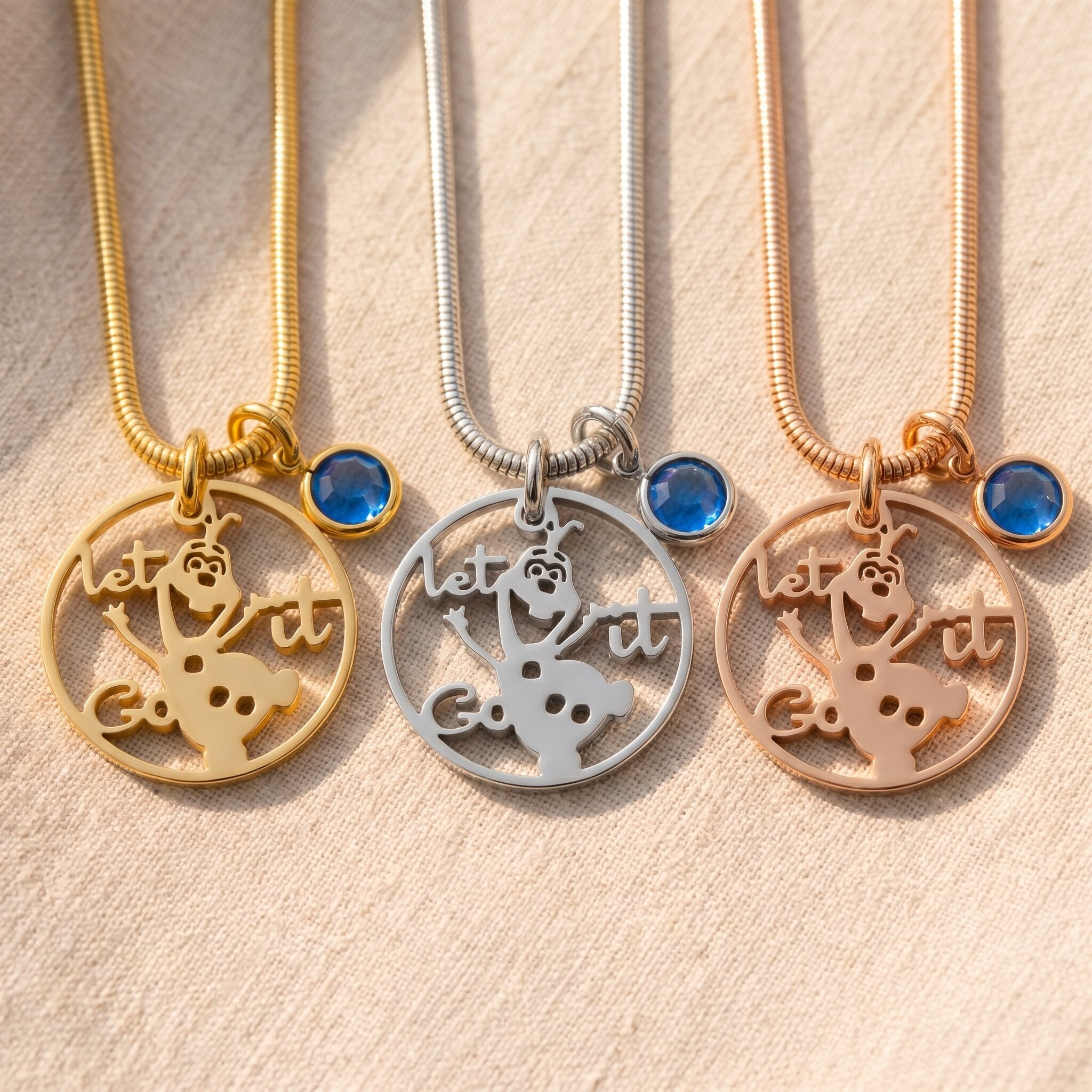 Melting snowman birthstone necklace tone comparison showing gold, silver and rose gold design finishes