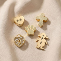 Moments charm bracelet charms in gold showing heart, cross and family symbol options