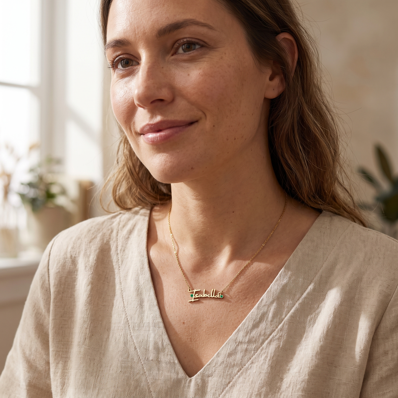 Personalised signature name necklace worn by a woman, featuring elegant handwritten-style lettering and a delicate gold chain
