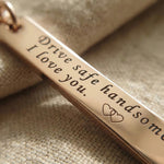Close-up of personalised tag keyring with engraved message on metal bar tag