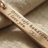 Close-up of personalised tag keyring with engraved message on metal bar tag