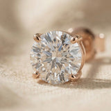 Close-up of round stud earrings with large sparkling stone and polished setting