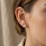 Woman wearing round stud earrings with sparkling stone, minimal everyday style